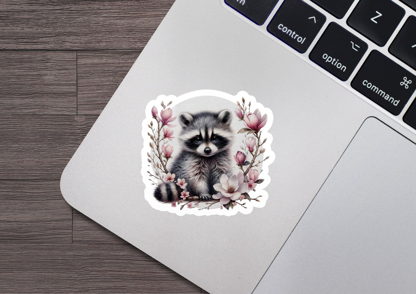 a sticker of a raccoon sitting on top of a laptop