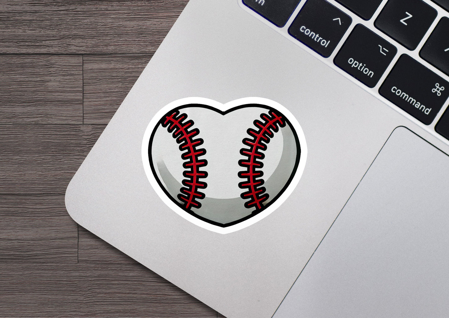 a heart shaped baseball sticker sitting on top of a laptop