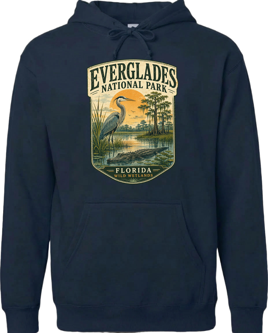 A hoodie with a graphic design depicting a bird standing in a marshy area with trees and a sunset in the background.