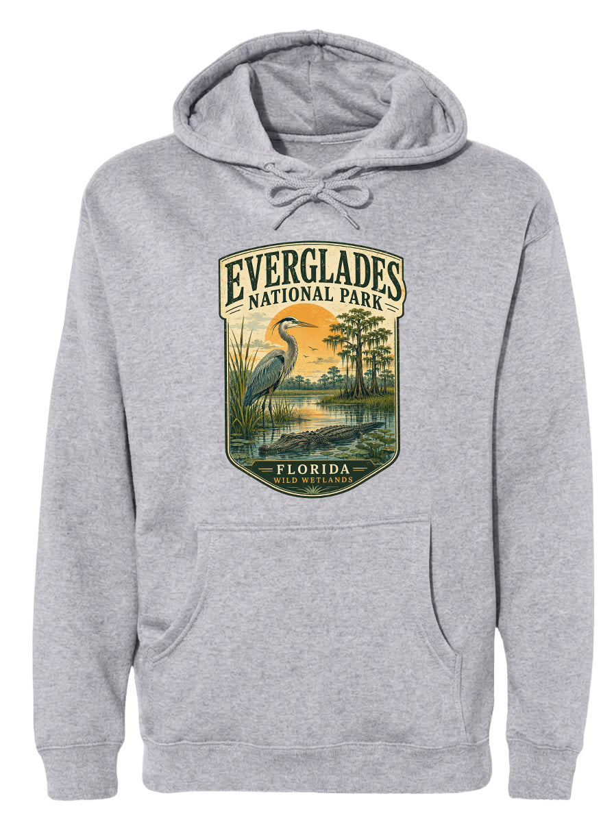 A gray hoodie with a graphic design depicting a bird, likely a heron, standing in a marshy area with a sunset in the background.