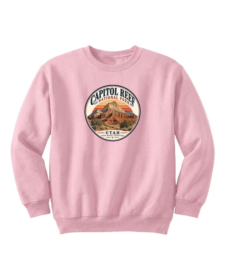 A pink sweatshirt with a circular design featuring a mountain and the text "CAPITOL REEF NATIONAL PARK UTAH" printed on it.