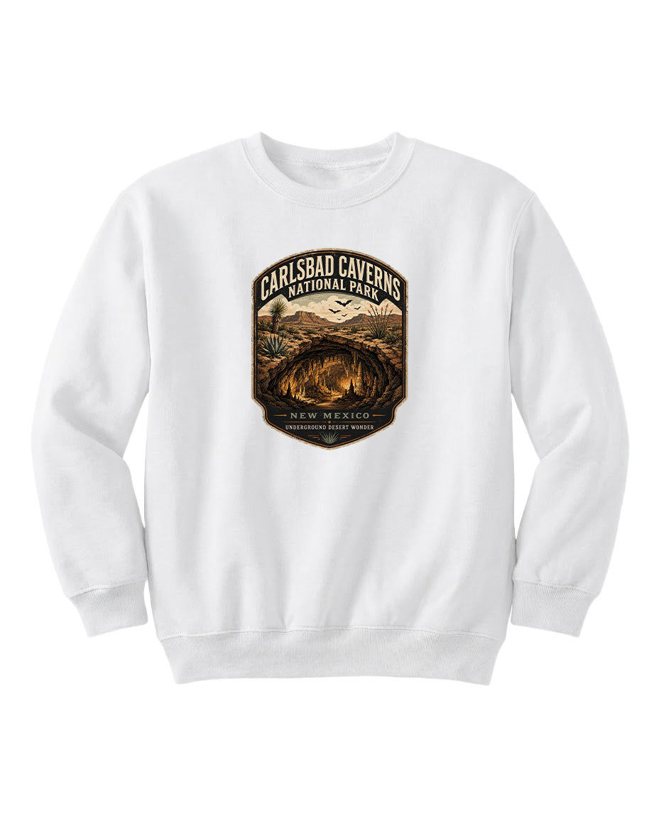 A white sweatshirt with a graphic design featuring a desert landscape and the text "CARLSBAD CAVENS NATIONAL PARK NEW MEXICO UNDERGROUND WONDER".
