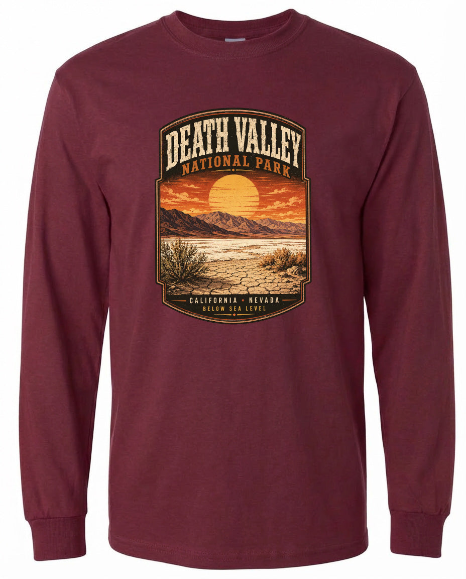 A long-sleeved burgundy t-shirt with a graphic design depicting a desert landscape with a sunset and mountains in the background.