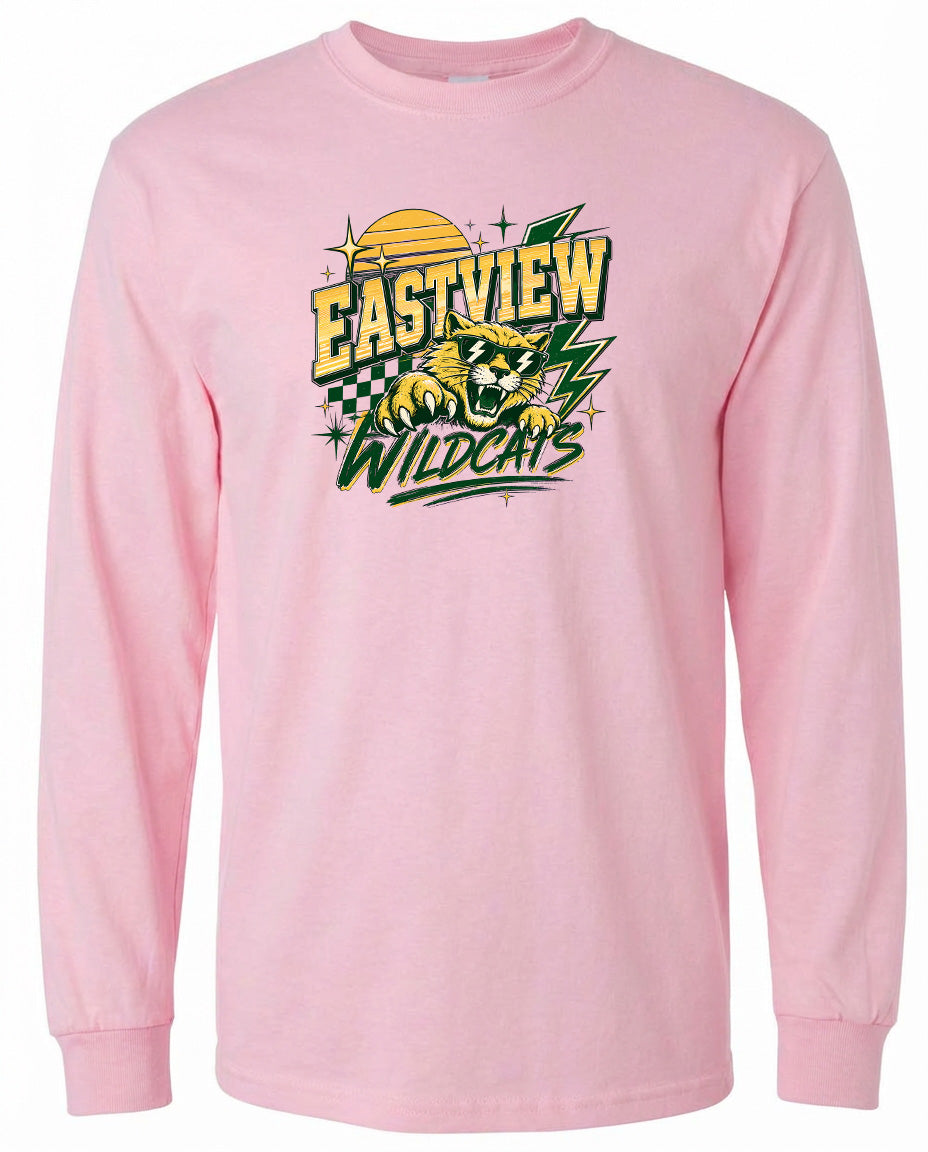 A pink long-sleeved t-shirt with a graphic design featuring a yellow and green checkered pattern, a yellow sun, and a graphic of a wildcat.