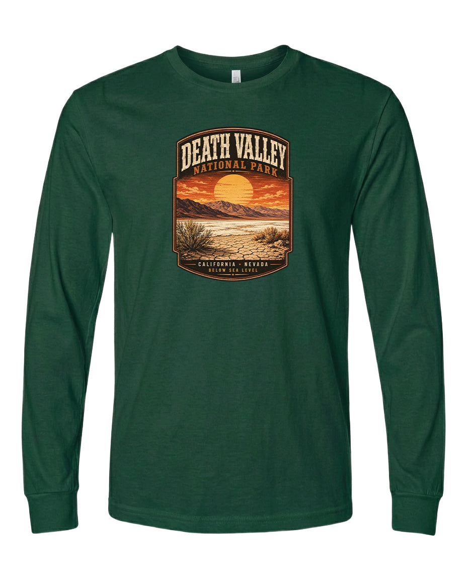 A long-sleeved green t-shirt with a graphic design depicting a desert landscape with a sunset and mountains in the background.