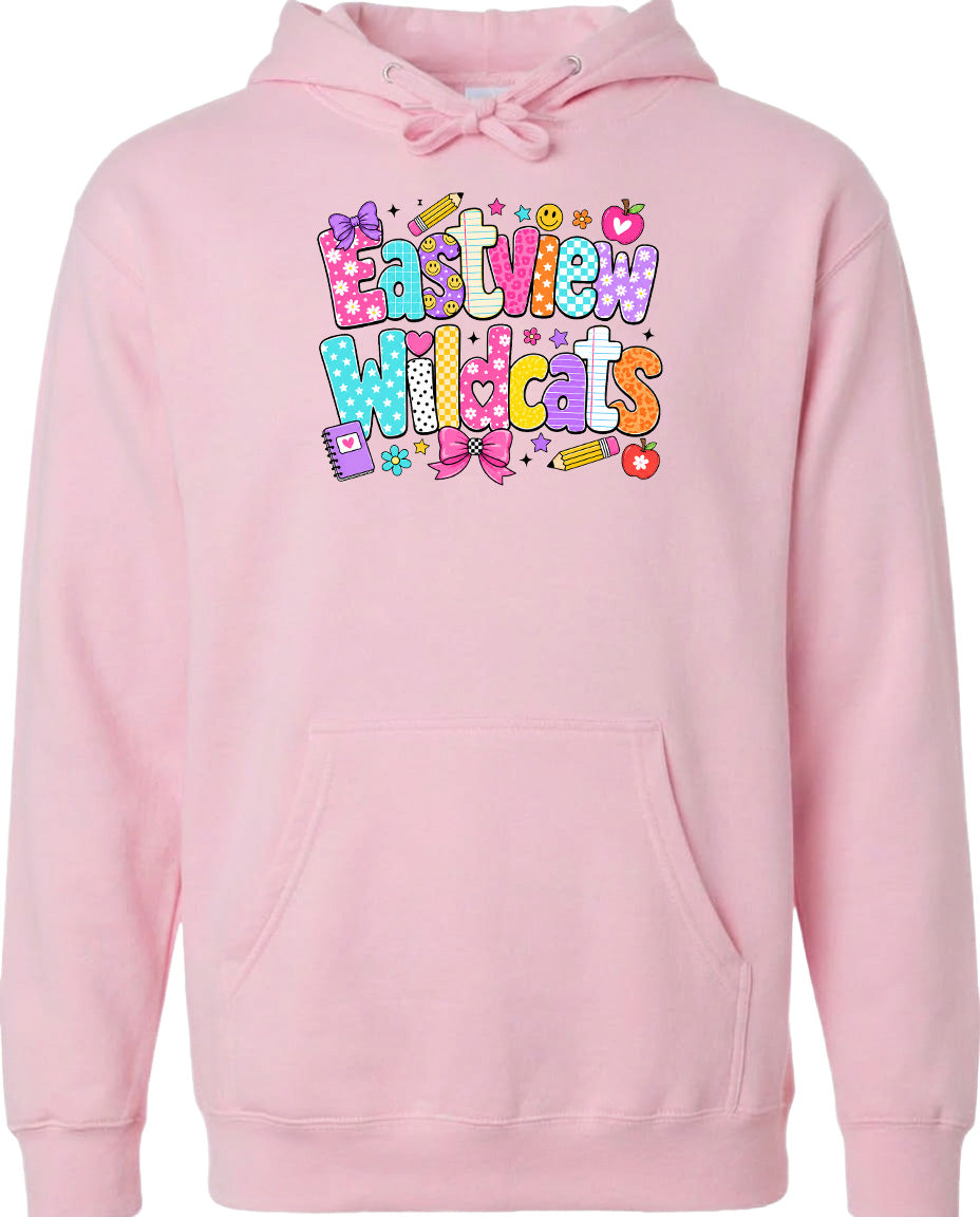 A pink hoodie with a colorful graphic design featuring the text "Eastview Wildcats" and various school-related icons such as pencils, books, and a backpack.