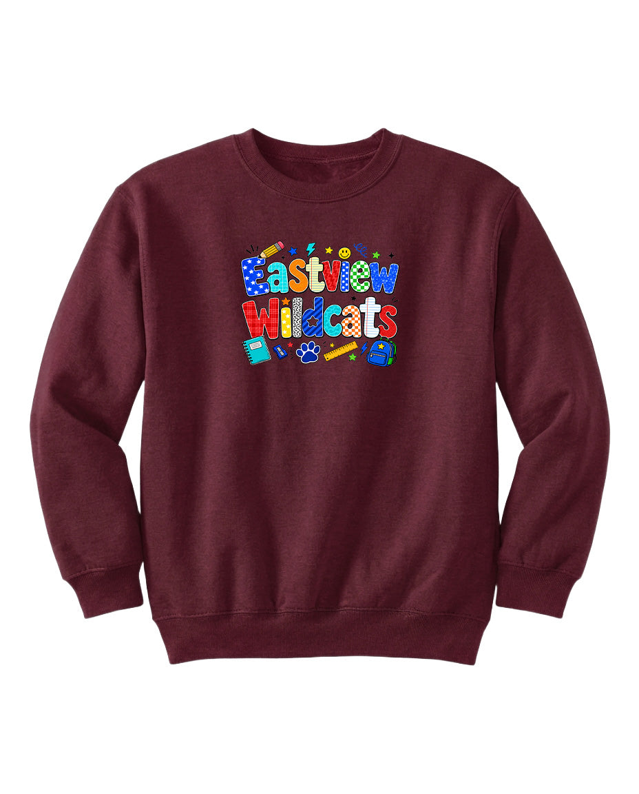 A burgundy sweatshirt with a colorful graphic design featuring the text "Eastview Wildcats" and various school supplies such as pencils, backpacks, and a calculator.