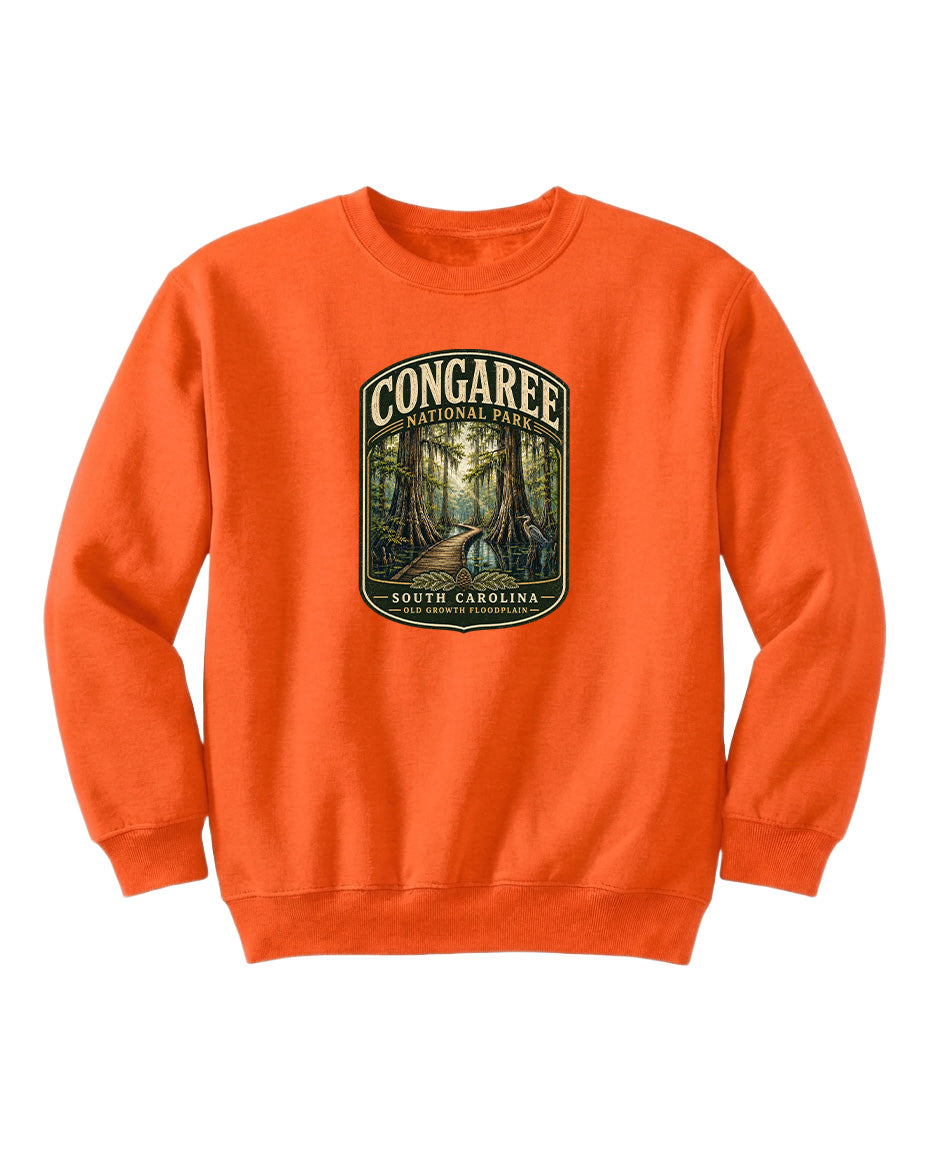 An orange sweatshirt with a graphic design depicting a forest scene, featuring the text "CONGAREE NATIONAL PARK SOUTH CAROLINA" prominently displayed.