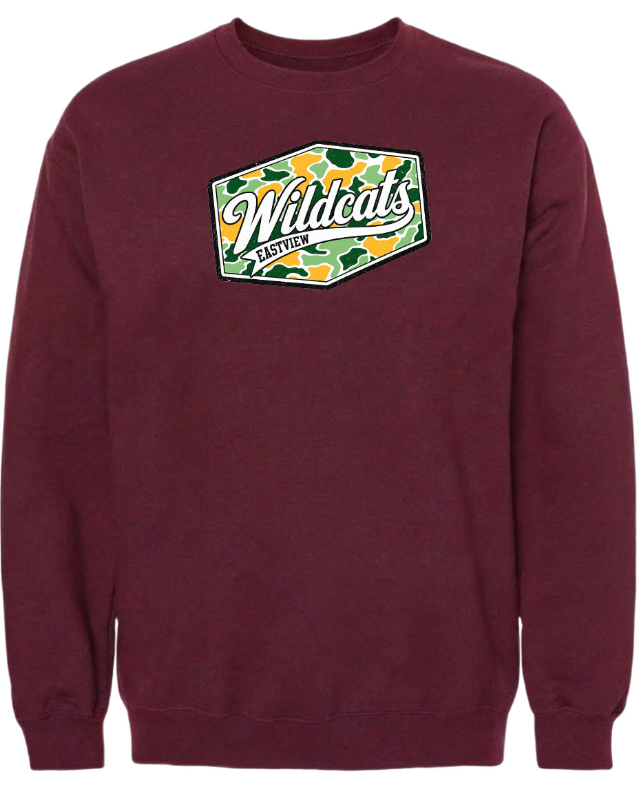 A burgundy-colored sweatshirt with a graphic design on the front. The design features a green and yellow camouflage pattern, and the text "Wildcats" is prominently displayed in a cursive font.