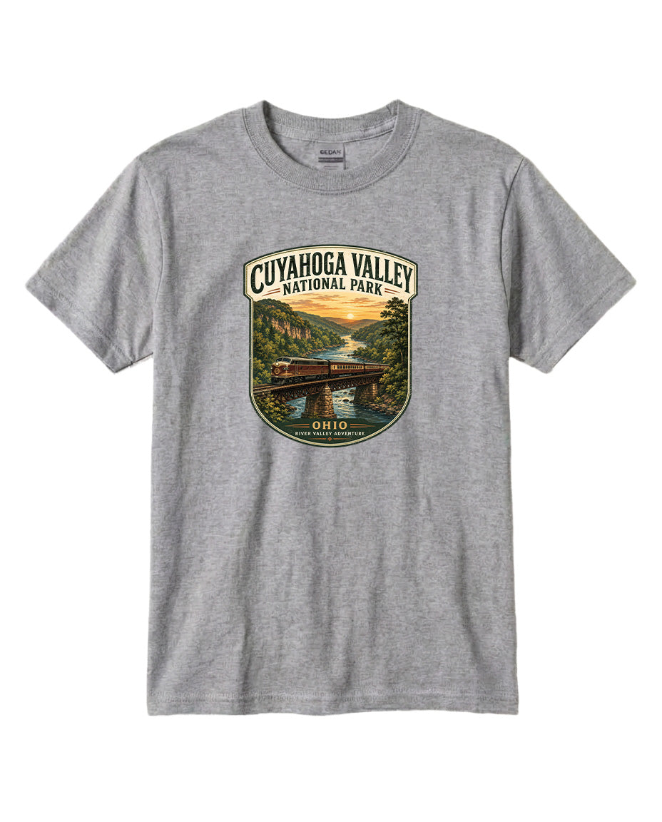 A gray t-shirt with a graphic design depicting a scenic view of the Cuyahoga Valley National Park, featuring a bridge, a river, and a sunset landscape.