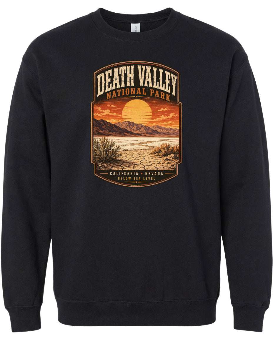 A black sweatshirt with a graphic design depicting a desert landscape with mountains, a sunset, and a desert plant.