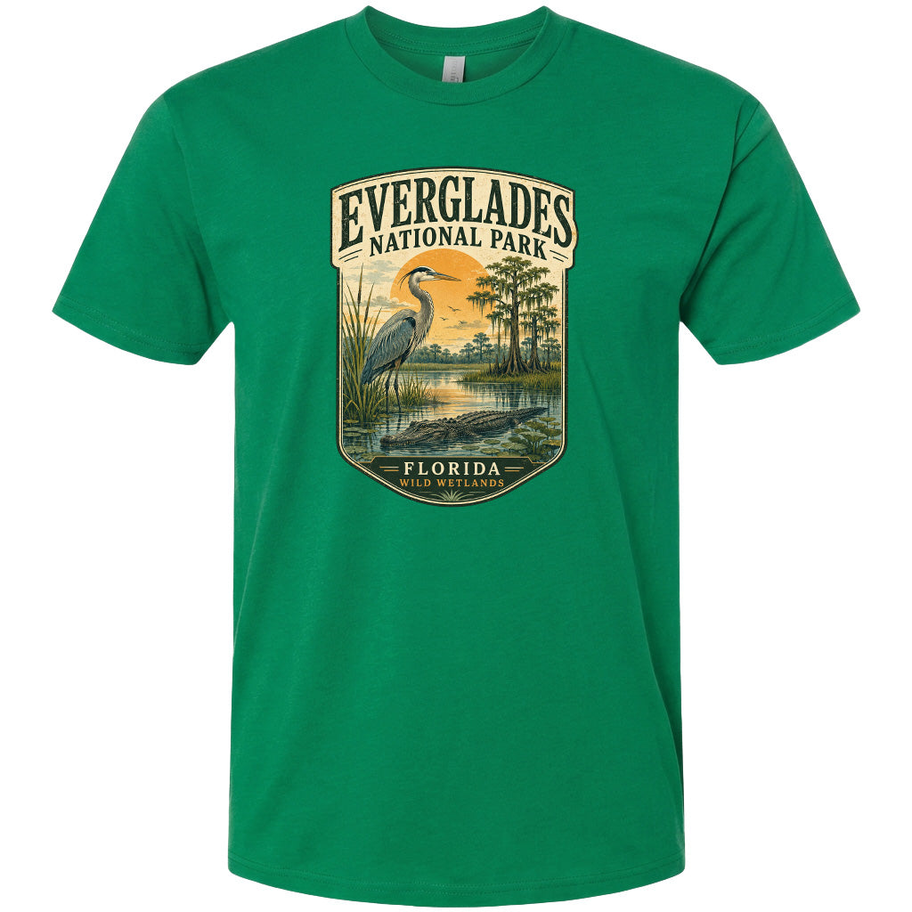 A green t-shirt with a graphic design depicting a bird, a water body, and a landscape with trees and a body of water.