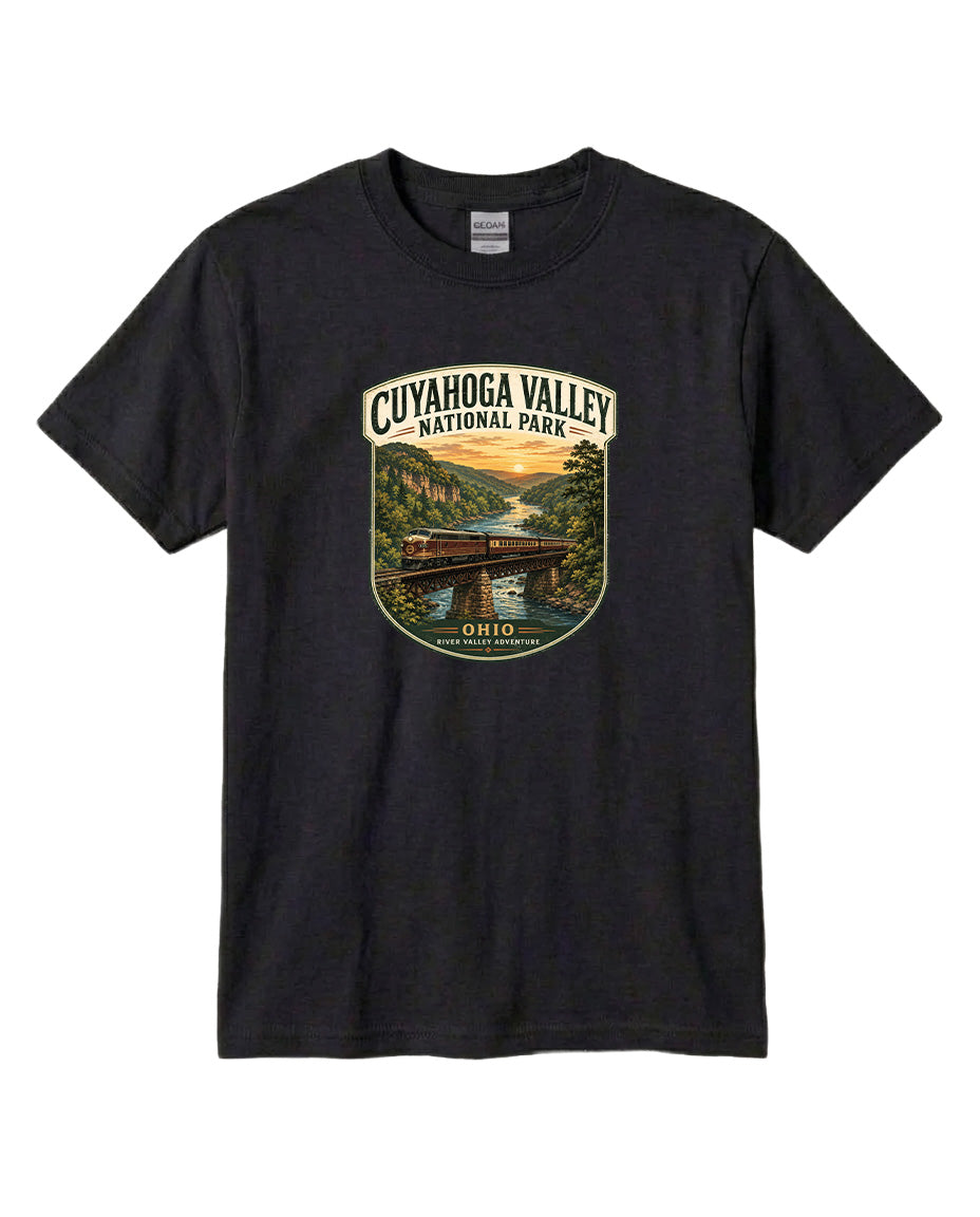 A black t-shirt with a graphic design depicting a scenic view of the Cuyaohoga Valley National Park, featuring a bridge, trees, and a sunset over a river.