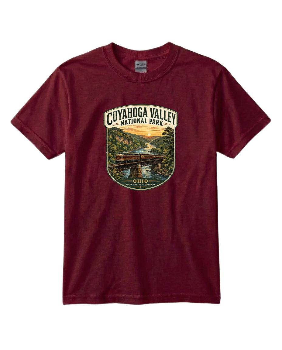 A burgundy-colored t-shirt with a graphic design depicting a scenic view of the Cuyahoga Valley National Park, featuring a bridge, trees, and a river.