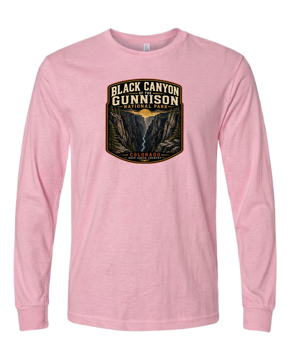 A pink long-sleeved t-shirt with a graphic design depicting the Black Canyon of the Gunnison National Park.