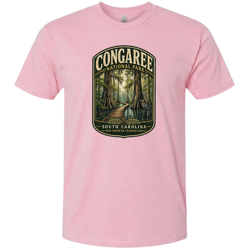 A pink t-shirt with a graphic design depicting a forest scene with a path leading through it, surrounded by trees and foliage.