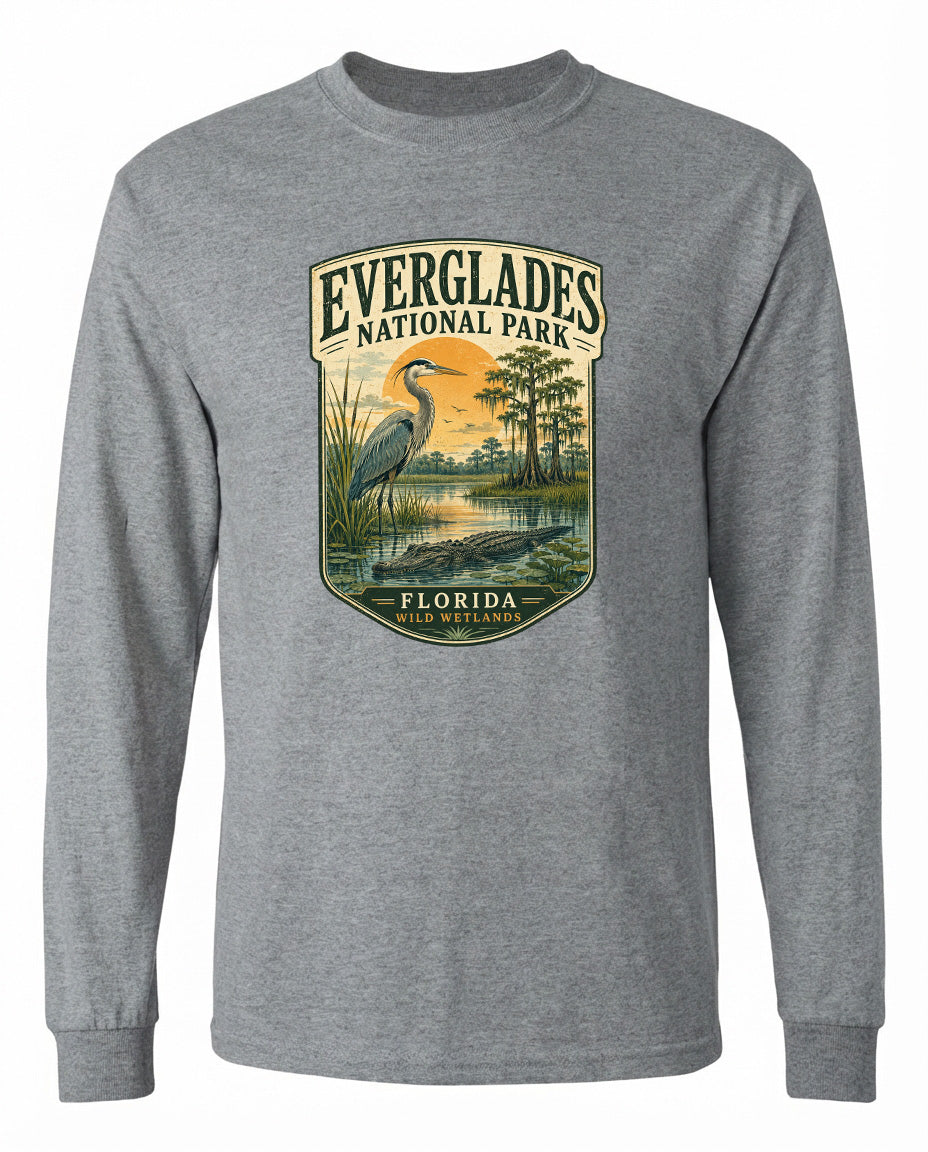 A gray long-sleeved t-shirt with a graphic design depicting a bird, likely a heron, standing in a natural setting with trees and a body of water.
