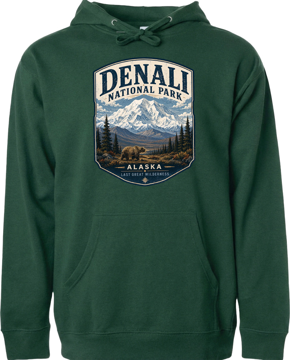 A green hoodie with a graphic design depicting Denali National Park in Alaska, featuring a mountain landscape with a bear in the foreground.