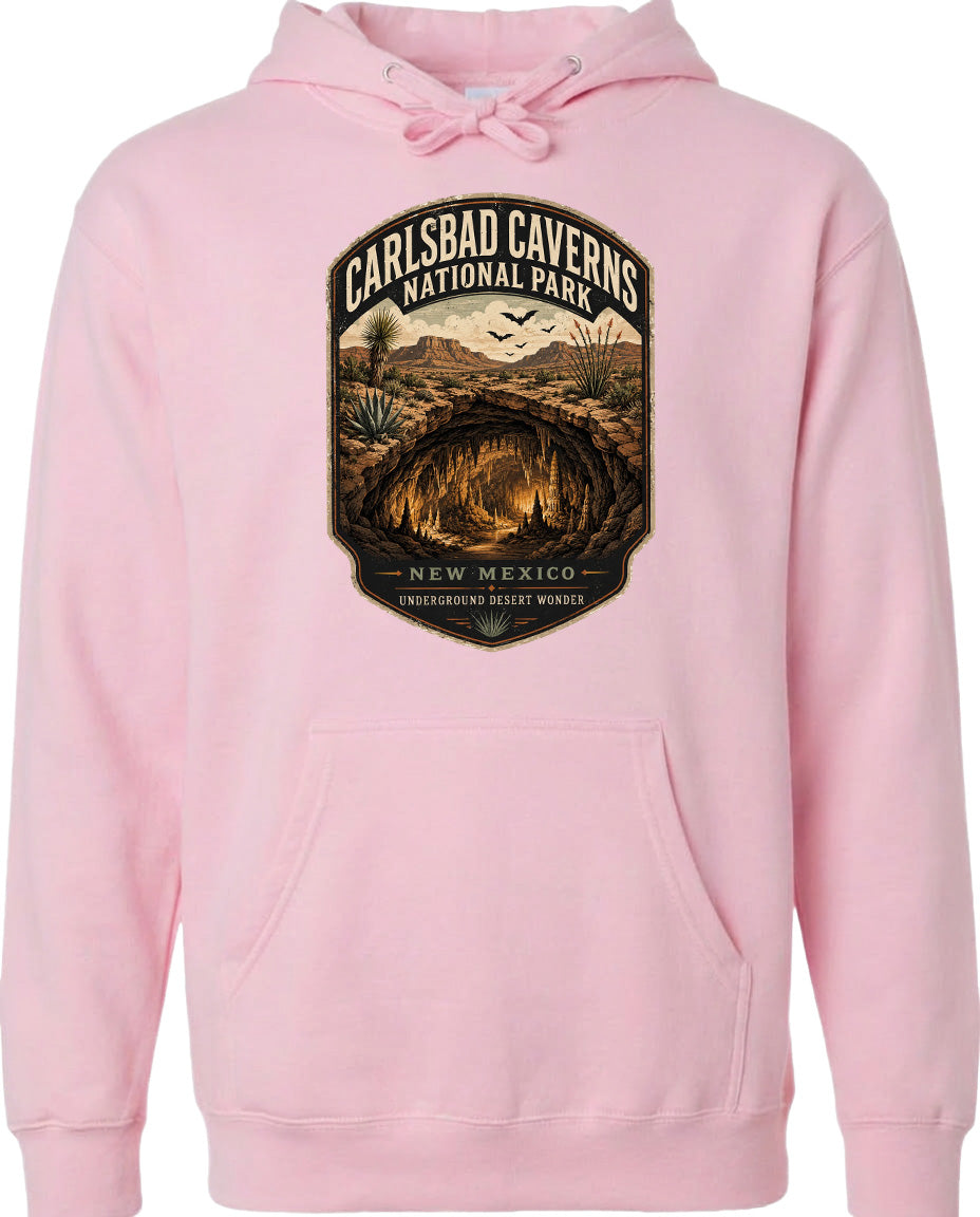 A pink hoodie with a graphic design depicting the Carlsbad Caverns National Park in New Mexico, featuring a desert landscape with a cave and birds in flight.
