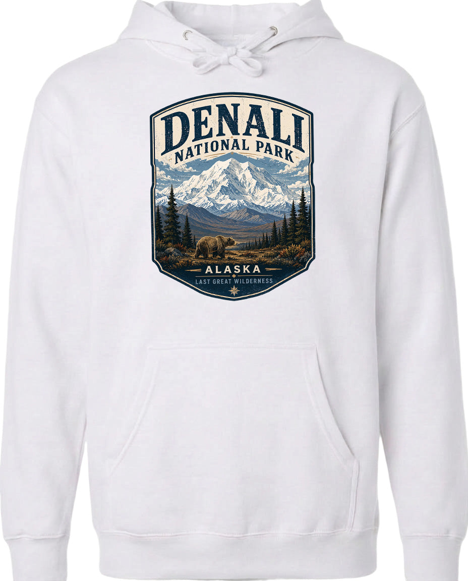 A white hoodie with a graphic design depicting Denali National Park in Alaska, featuring a mountain landscape with a bear in the foreground.
