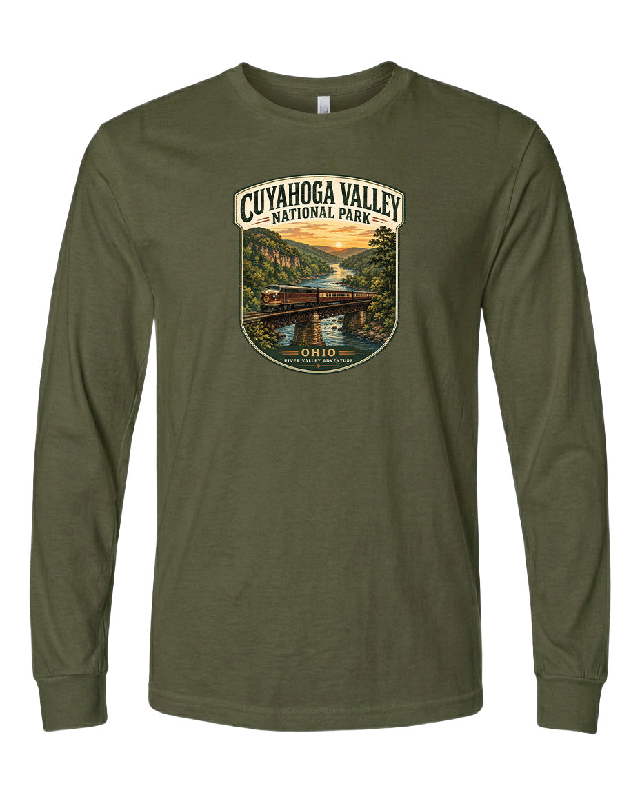 A long-sleeved olive green t-shirt with a graphic design depicting a scenic view of the Cuyahoga Valley National Park, featuring a bridge, trees, and a sunset.