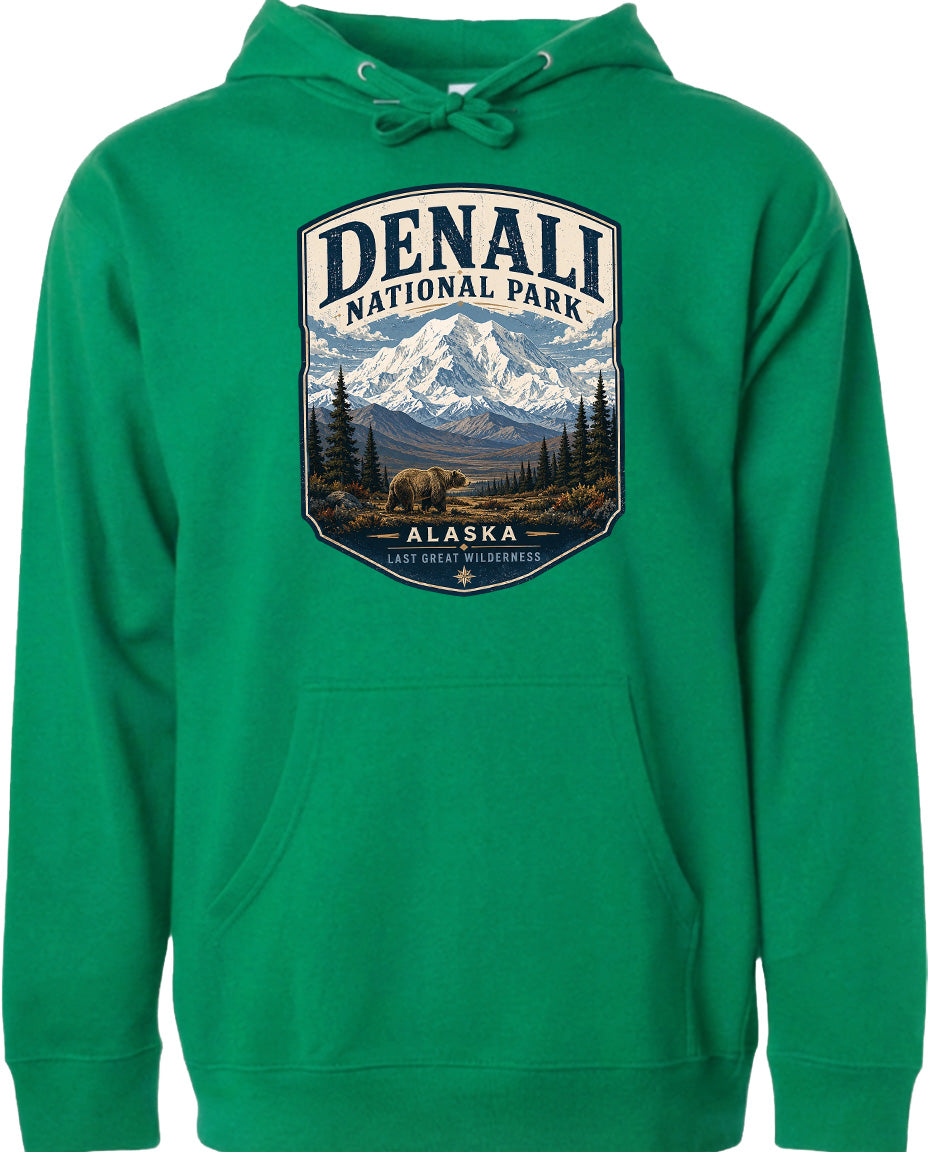 A green hoodie with a graphic design depicting Denali National Park in Alaska, featuring a mountain landscape with a bear in the foreground.
