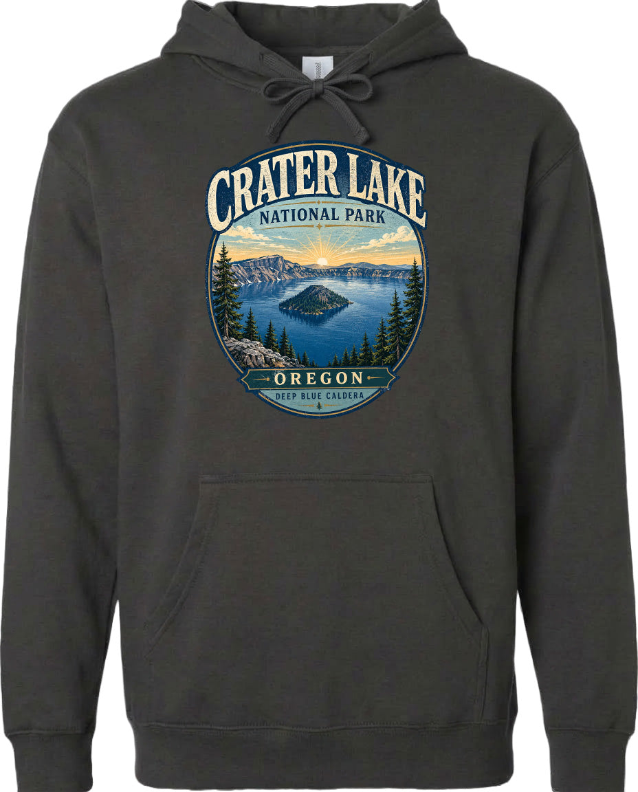 A hoodie with a graphic design featuring a scenic landscape with a lake, mountains, and trees, along with the text "Crater Lake National Park, Oregon" and "Keep Blue Caldera".