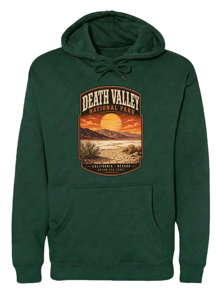 A green hoodie with a graphic design depicting Death Valley National Park, including a sunset over the mountains and desert landscape.