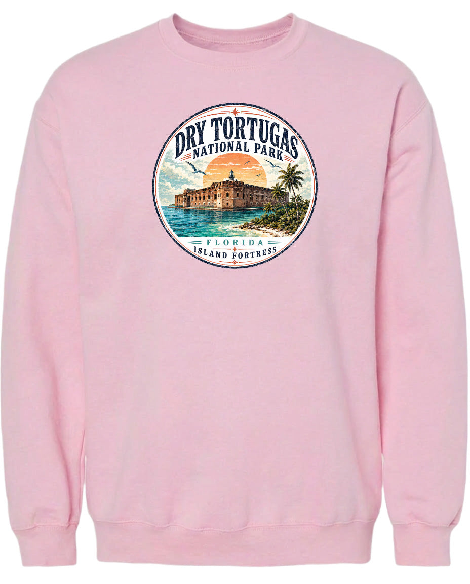 A pink sweatshirt with a circular graphic design featuring a building, palm trees, and a sunset over the ocean.