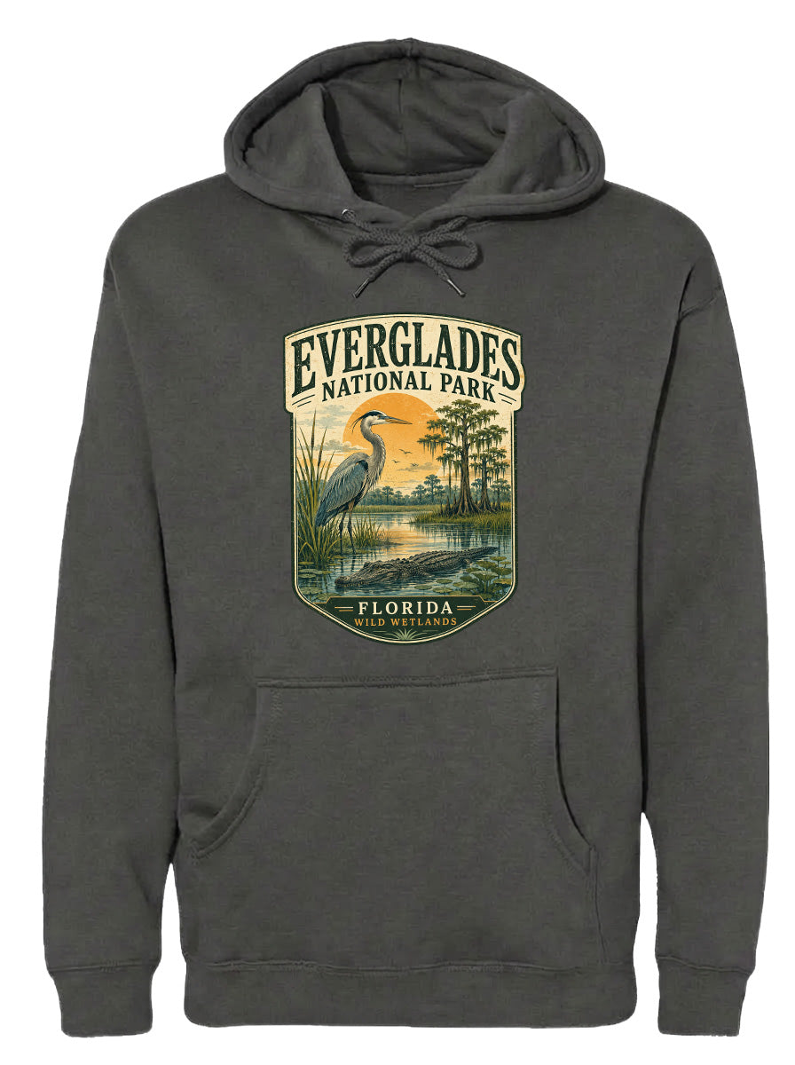 A gray hoodie with a graphic design depicting a bird standing in a pond surrounded by trees and a sunset.