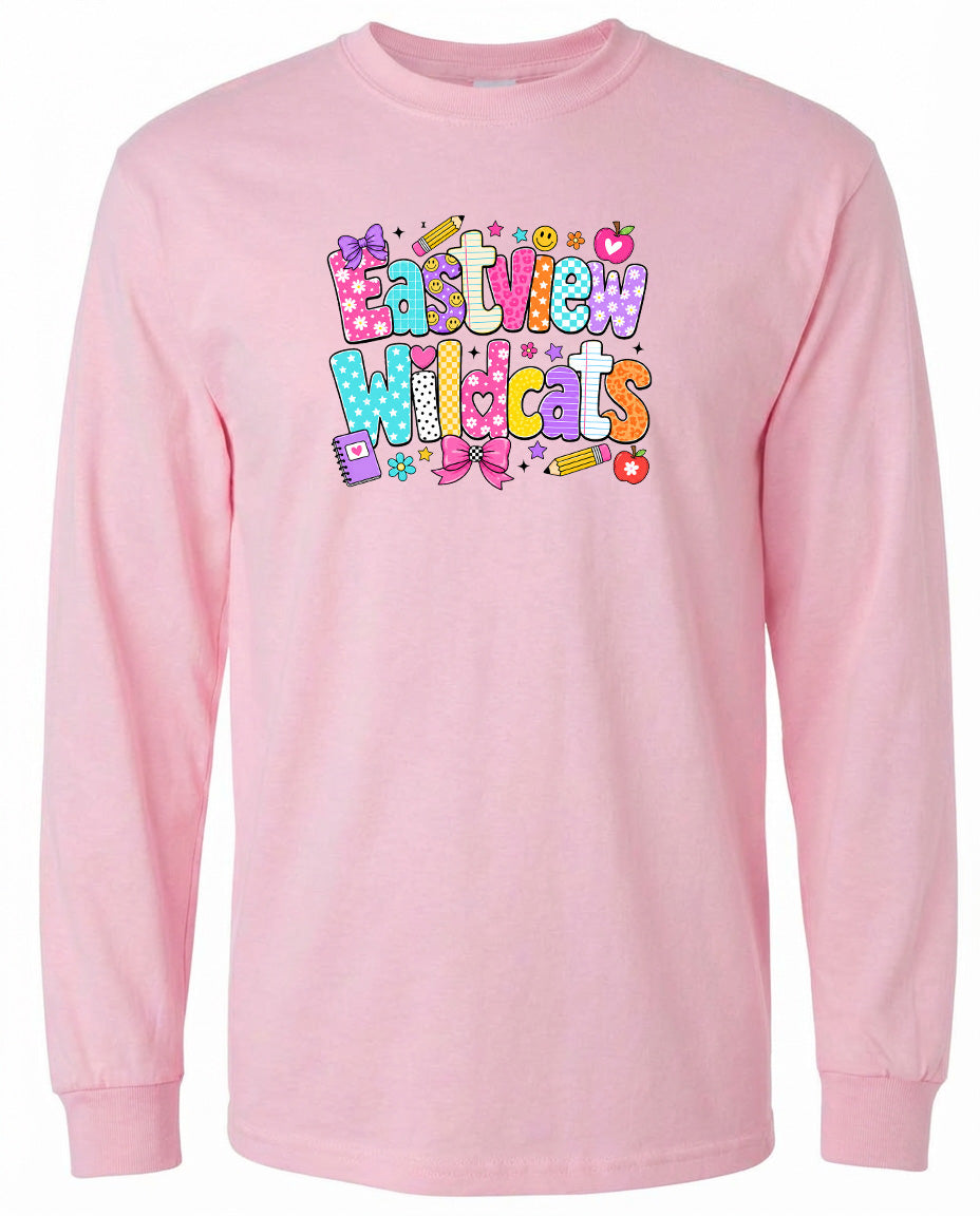 A pink long-sleeved shirt with a colorful graphic design featuring the text "Eastview Wildcats" and various decorative elements such as stars, hearts, and flowers.