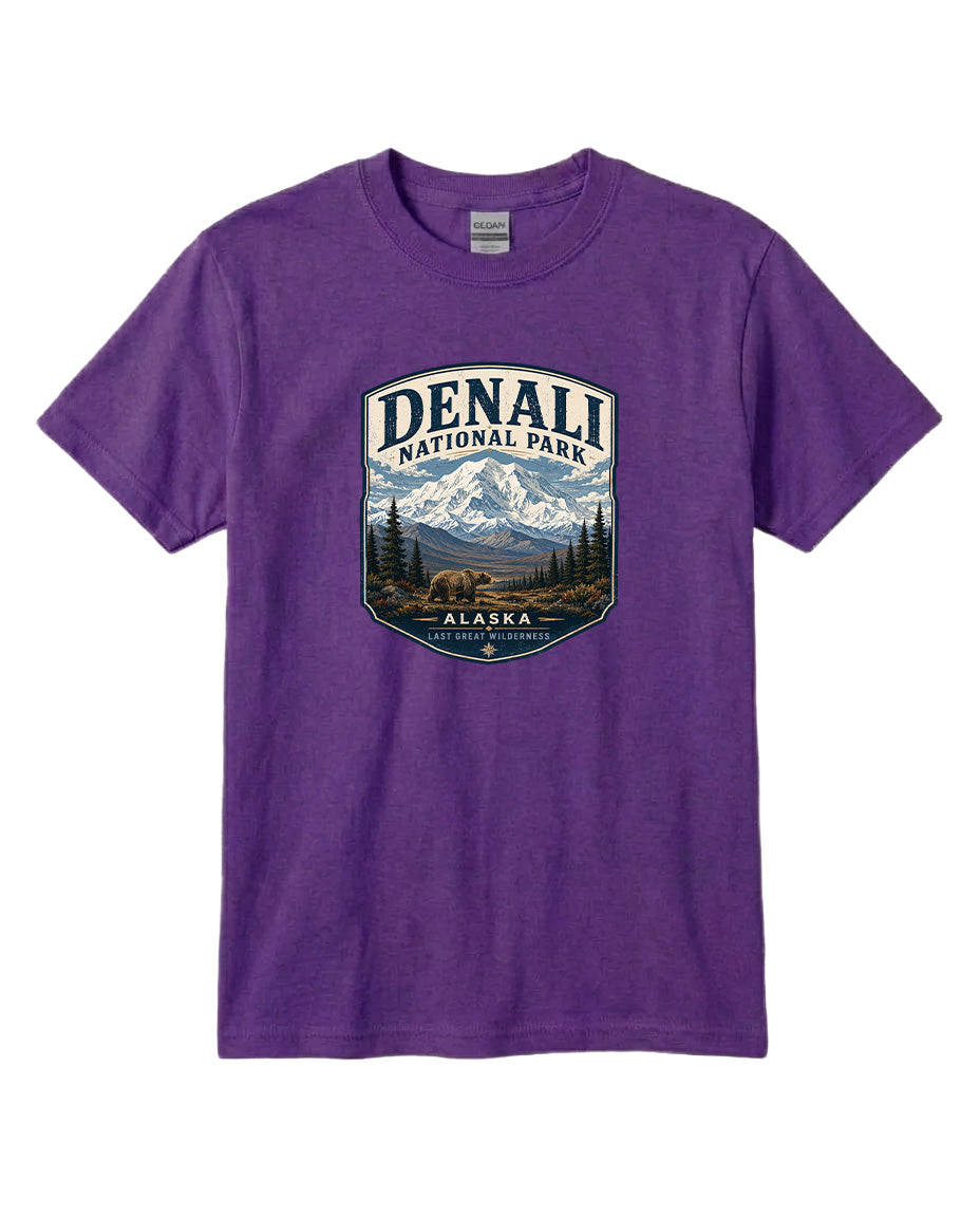 A purple t-shirt with a graphic design depicting a mountain landscape and bears, along with the text "DENALI NATIONAL PARK ALASKA LAST GREAT WILDERNESS".
