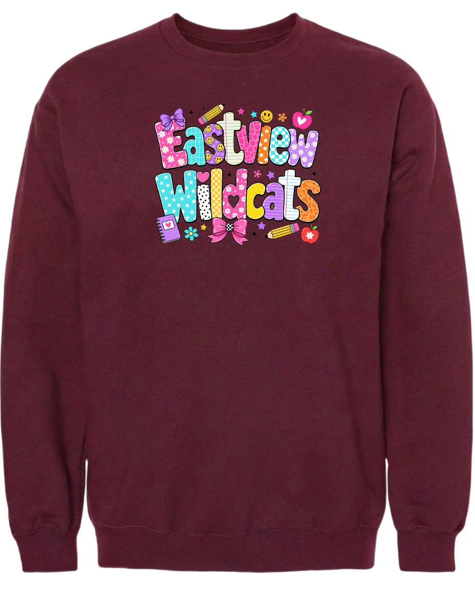 A burgundy sweatshirt with a colorful graphic design featuring the text "Eastview Wildcats" and various decorative elements such as hearts, stars, and flowers.