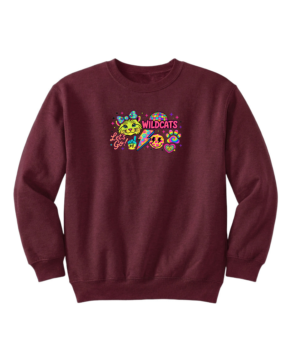 A burgundy sweatshirt with a colorful graphic design featuring a smiling face, a cat, and the text "WILDCATS" along with a smiley face.