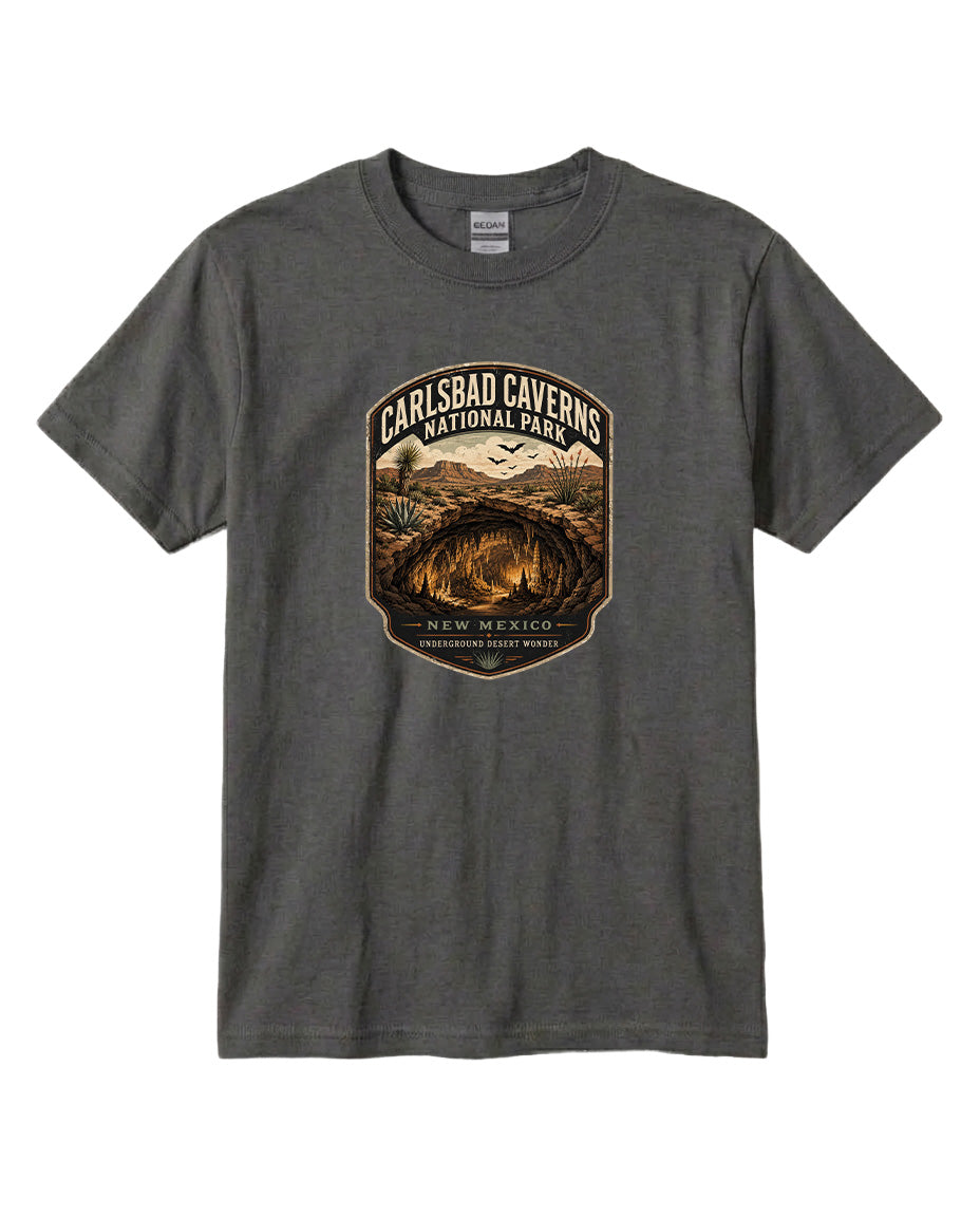 A gray t-shirt with a graphic design featuring a cave and mountains, along with text that says "CARLSBAD CAVENS NATIONAL PARK NEW MEXICO UNDERGROUND WONDERS".