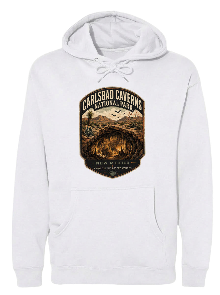 A white hoodie with a graphic design depicting the Carlsbad Caves National Park in New Mexico, featuring a desert landscape with a cave and birds in the background.