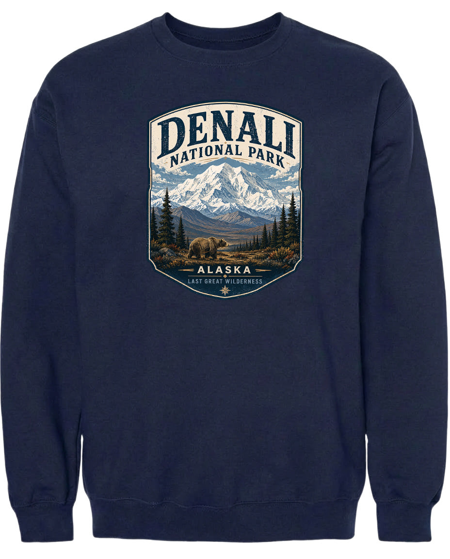 A navy blue sweatshirt with a graphic design depicting a bear in the foreground, surrounded by a mountainous landscape with pine trees and snow-capped peaks.