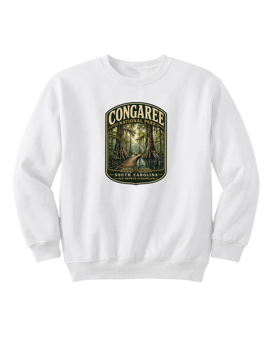 A white sweatshirt with a graphic design depicting a forest scene, featuring the text "CONGAREE NATIONAL PARK SOUTH CAROLINA" prominently displayed.