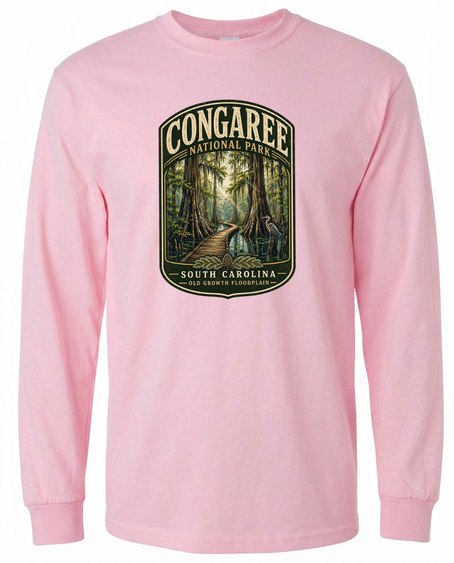 A pink long-sleeved t-shirt with a graphic design depicting a forest scene, featuring a path leading through the trees.