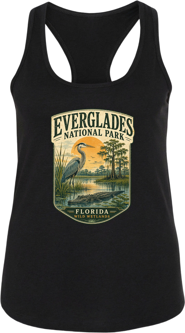 A black tank top with a graphic design depicting a bird, likely a heron, standing in a marshy area with a sunset in the background. The text "EVERGLADES NATIONAL PARK" and "FLORIDA" is visible, indicating the location of the design.