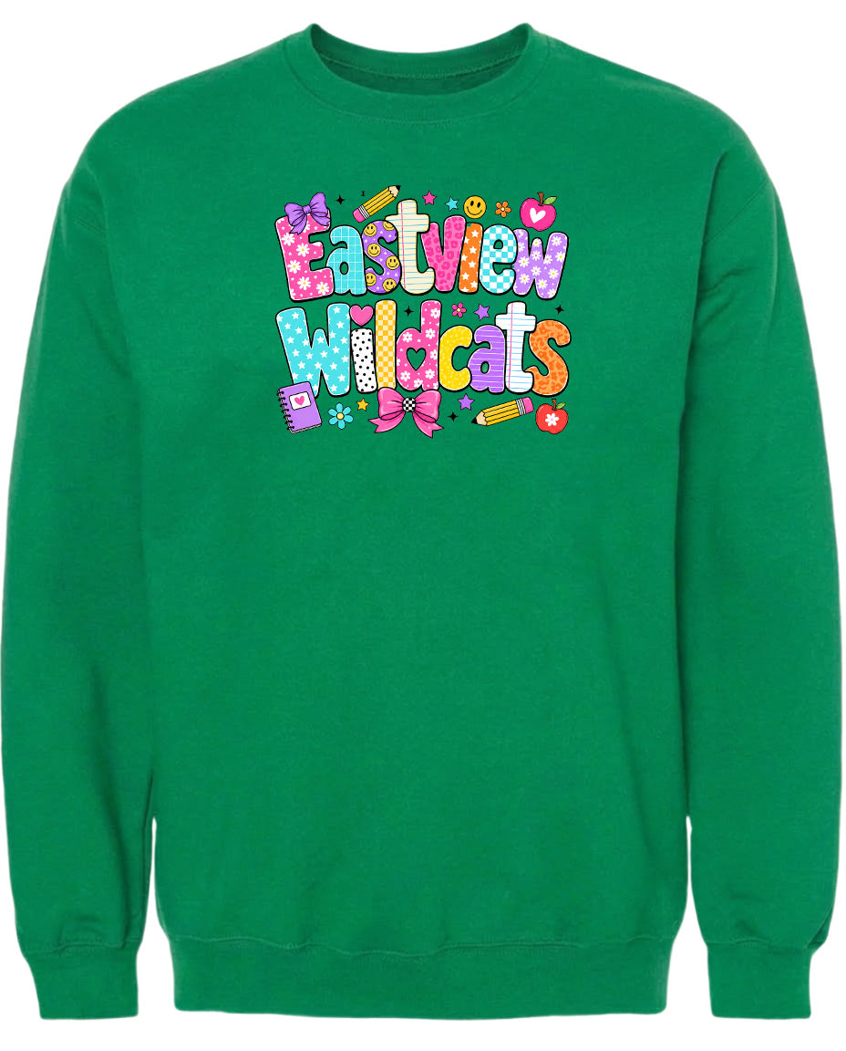 A bright green sweatshirt with a colorful graphic design featuring the text "Eastview Wildcats" and various decorative elements such as hearts, pencils, and flowers.