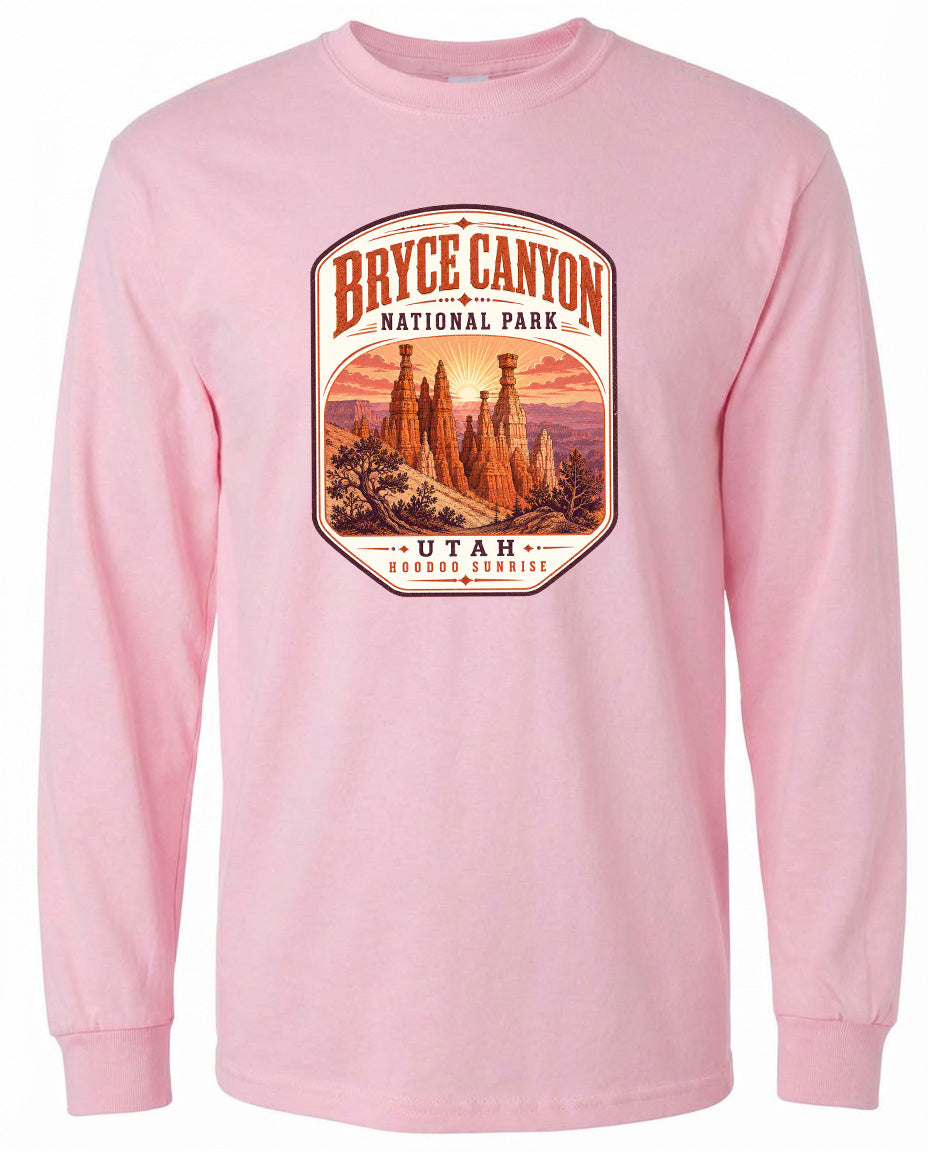 A pink long-sleeved t-shirt with a graphic design depicting the Bryce Canyon National Park in Utah, featuring the iconic hoodoos and the sunrise.