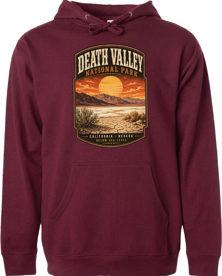 A burgundy-colored hoodie with a graphic design depicting a desert landscape with mountains, a sunset, and a cactus plant.