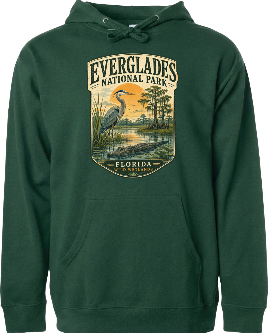 A green hoodie with a graphic design depicting a heron and a sunset over Everglades National Park, Florida.