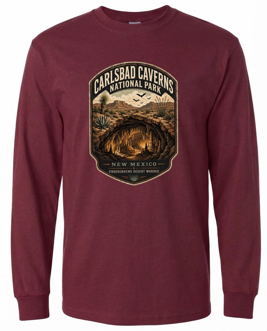 A long-sleeved burgundy t-shirt with a graphic design featuring a cave or cave system surrounded by desert landscape elements, including mountains, cacti, and birds.