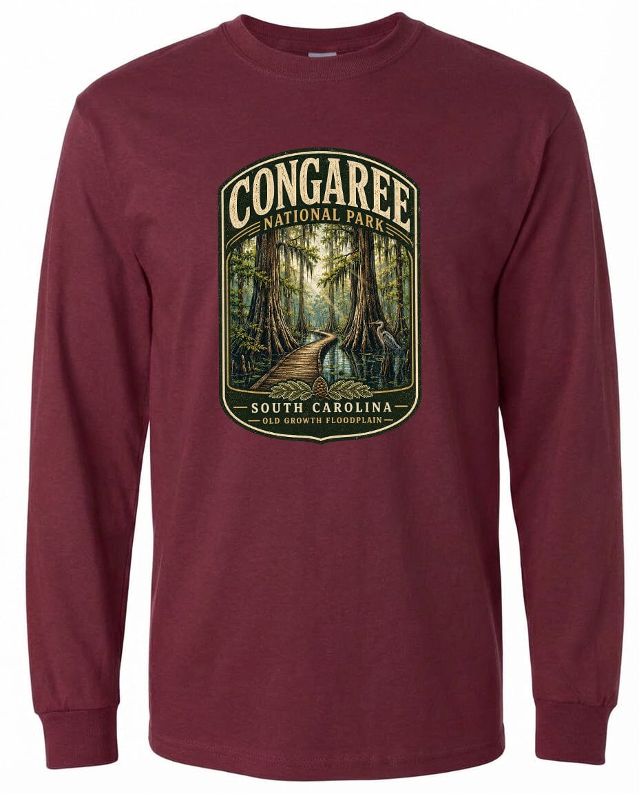 A long-sleeved burgundy t-shirt with a graphic design depicting a forest path leading through a lush, green landscape.