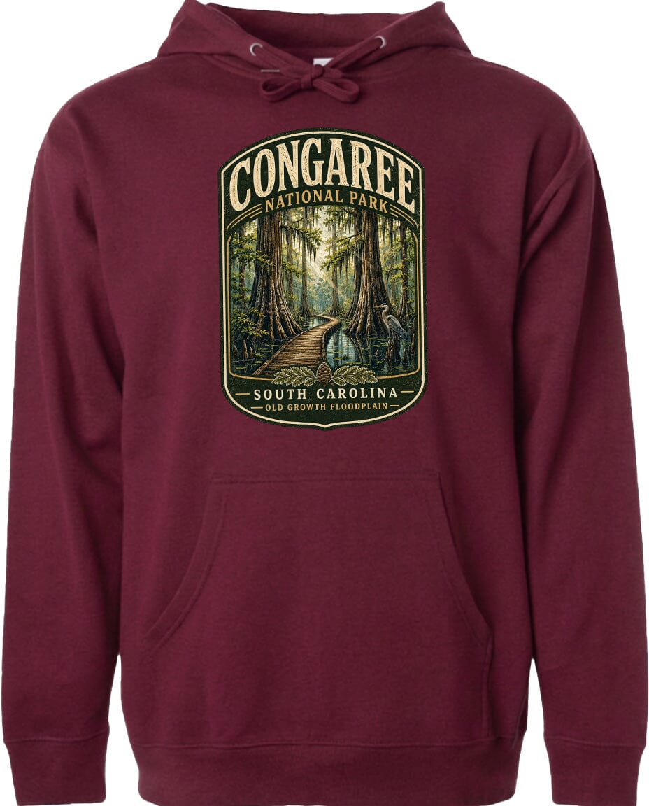 A maroon hoodie with a graphic design depicting a forest scene, including a path leading through the trees and a bird in flight.