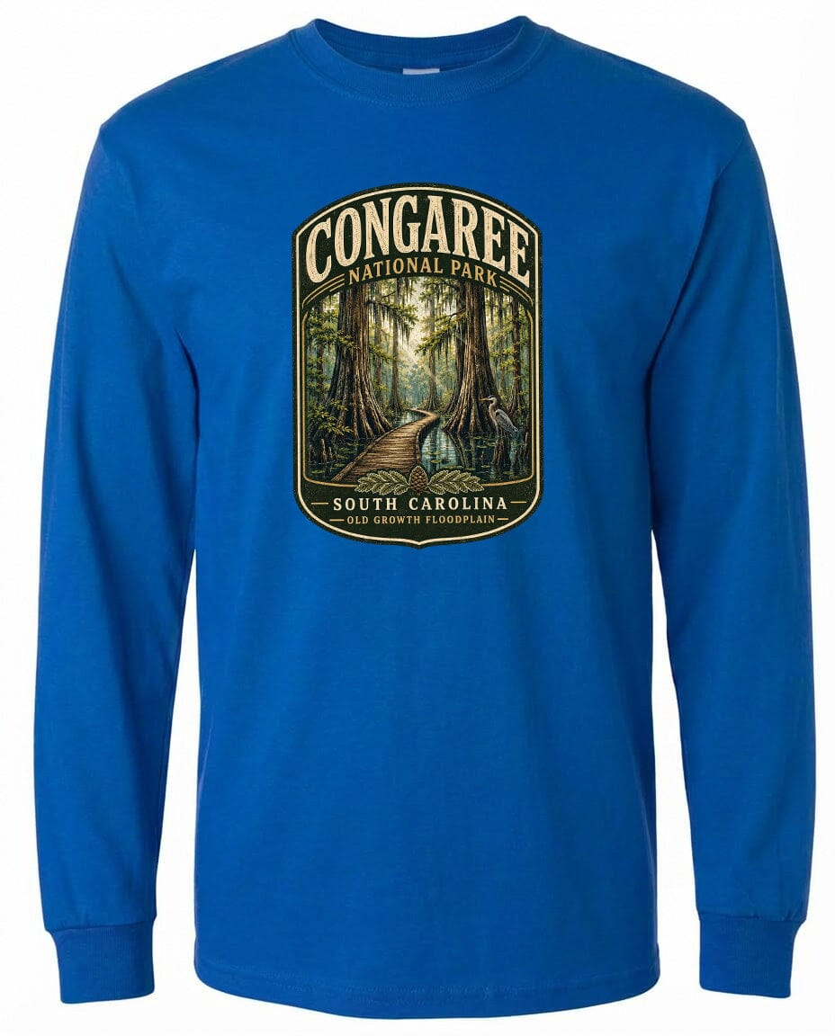 A blue long-sleeved t-shirt with a graphic design depicting a forest path leading through the Congaree National Park in South Carolina.