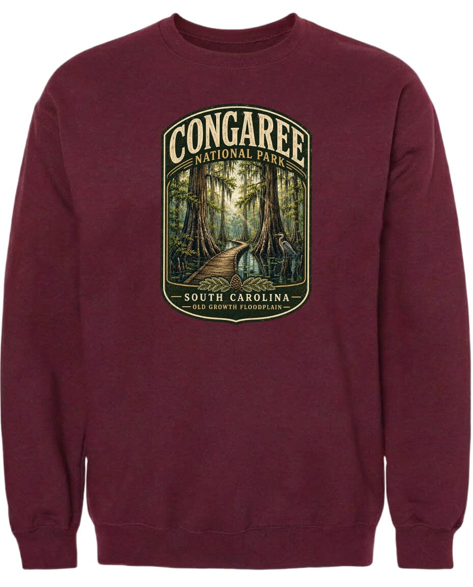 A burgundy sweatshirt with a graphic design depicting a forest scene, featuring a path leading through the trees and a bird in flight.