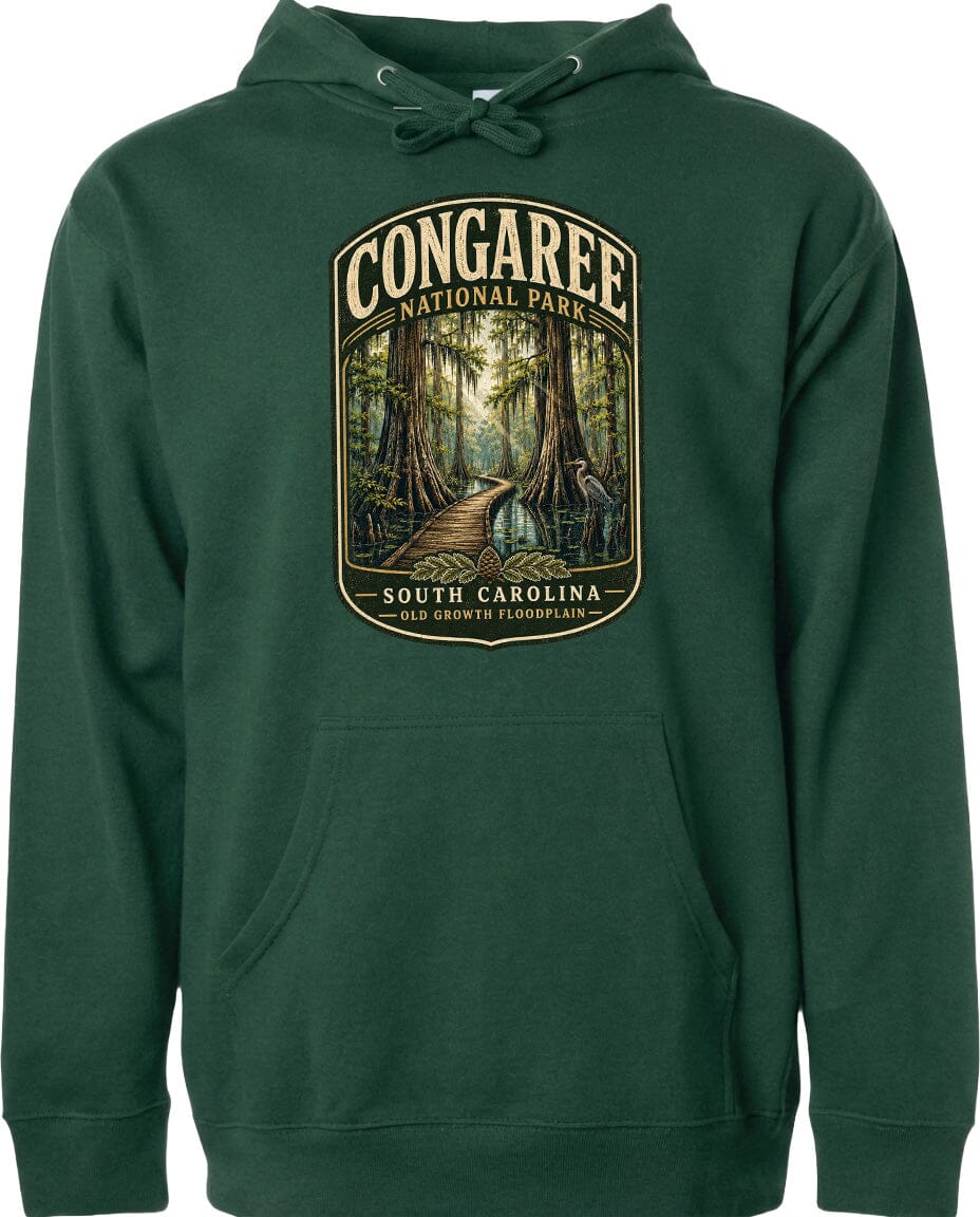 A green hoodie with a graphic design depicting a forest scene and a path leading through it, along with the text "CONGAREE NATIONAL PARK SOUTH CAROLINA".